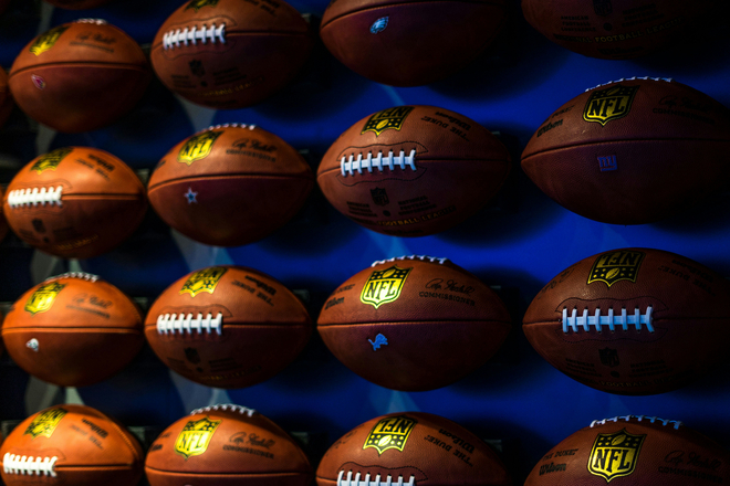 NFL footballs displayed against a blue wall.