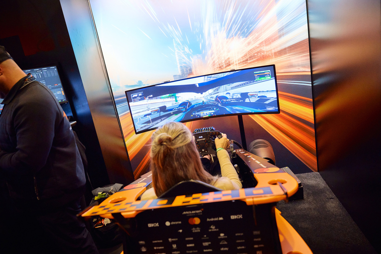 Women plays racing video game in seat designed to look like a racing car.